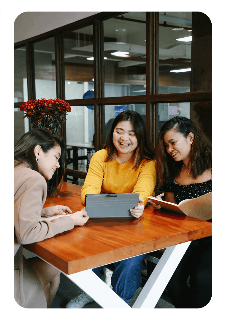 three women looking at a tablet sitting on